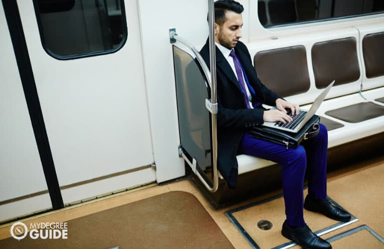 male professional working on his computer while commuting to work