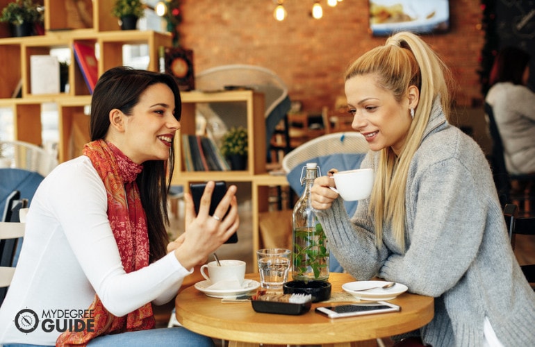 two female colleagues drinking coffee at a cafe