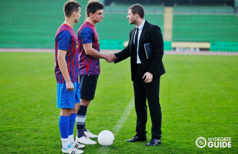 sports manager talking to athletes in a soccer field
