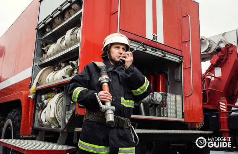 firefighter in action standing near a firetruck 