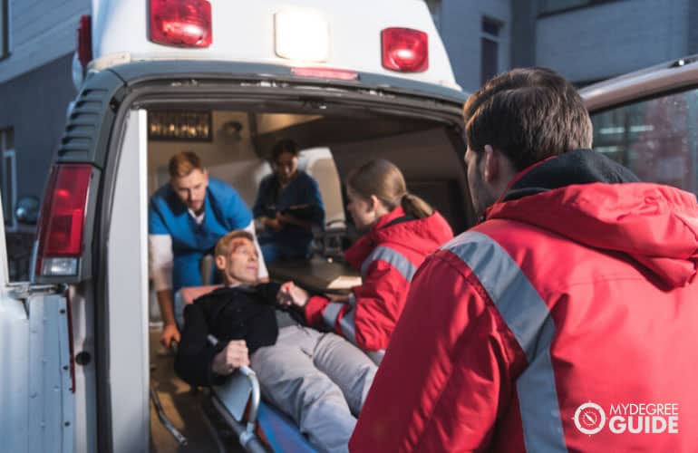 paramedics moving wounded man into ambulance