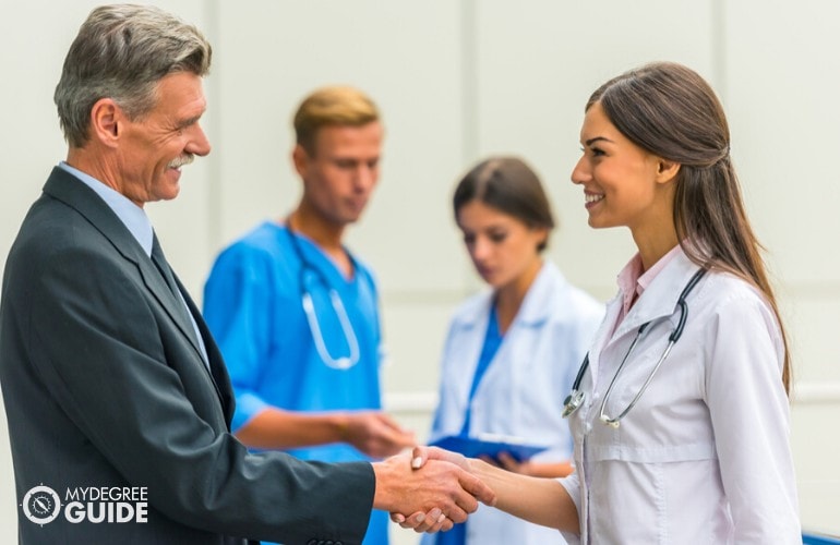 healthcare administrator shaking hands with a doctor