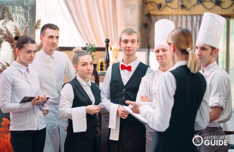 restaurant manager discussing with her staff in a commercial kitchen