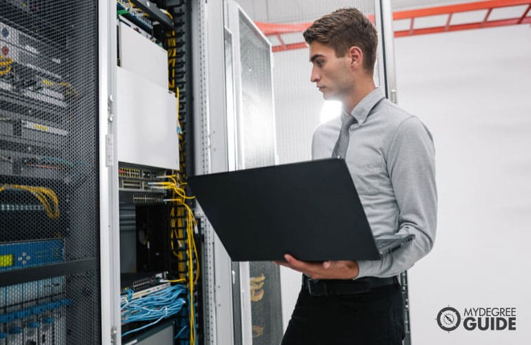 network systems administrator working in data center with his laptop