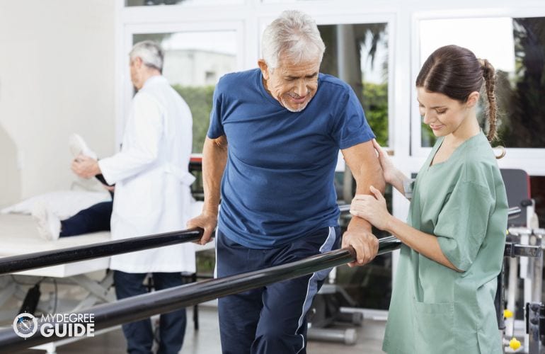 Physical Therapy Aide guiding a patient to stand