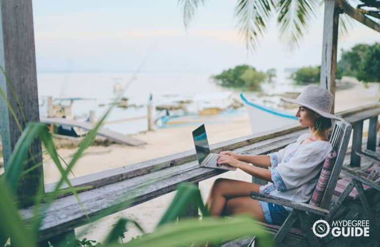 student studying on her computer at a beach