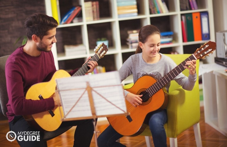 Music Teacher teaching a student to play guitar