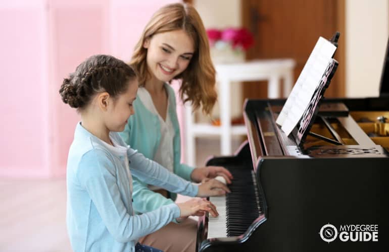 music teacher teaching her student how to play a piano