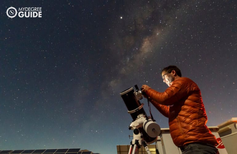 astronomer looking the night sky through an amateur telescope