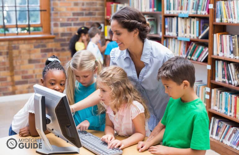 librarian teaching kids how to use computer