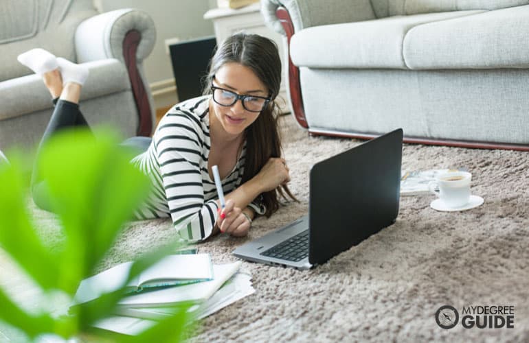female adult comfortably studying at home with computer and books 